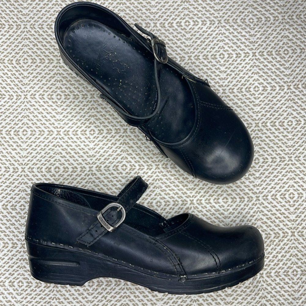 Dansko black clogs with buckled strap.